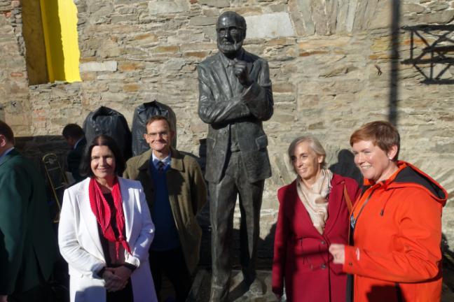 four UCD faculty stand in sun next to statue